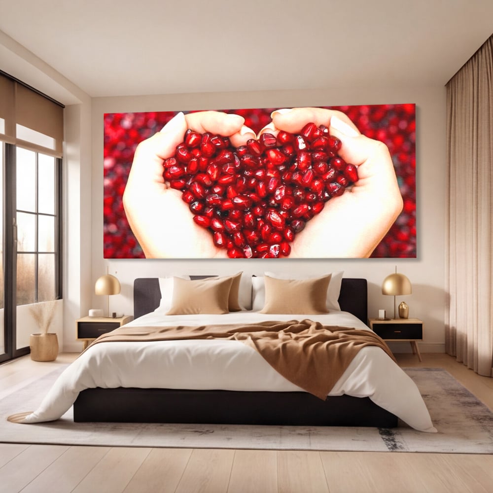 Tablou canvas cu maini care tin seminte de rodie in forma de inima, fara rama, pe sasiu de lemn, pe perete intr-un dormitor