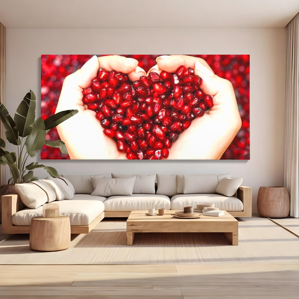 Tablou canvas cu maini care tin seminte de rodie in forma de inima, fara rama, pe sasiu de lemn, pe perete intr-un living