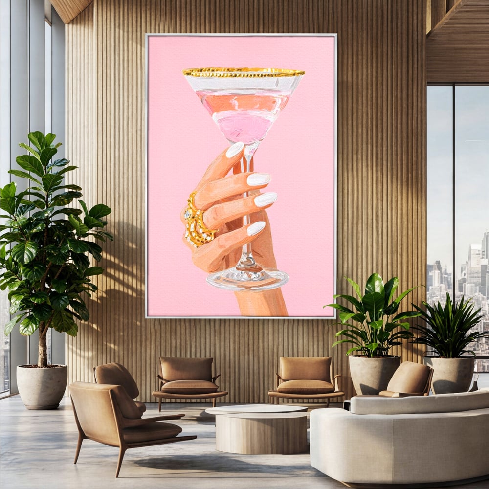 Tablou canvas cu ilustratie cu mana care tine pahar de cocktail, in rama de aluminiu argintiu, pe perete intr-un birou
