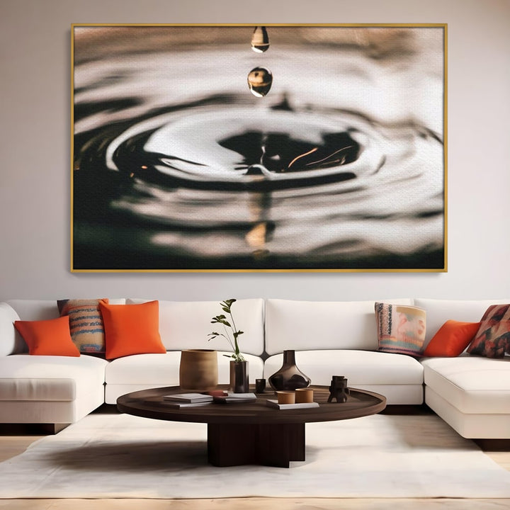 Tablou canvas cu picatura de apa cazand in valuri, in rama de aluminiu auriu, pe perete intr-un living