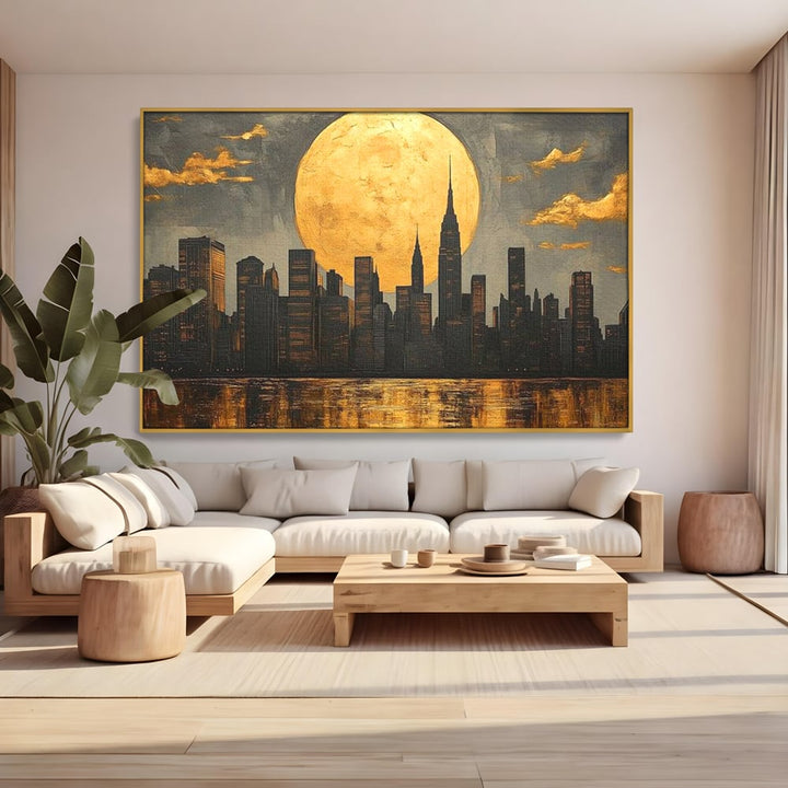 Tablou canvas cu pictura orizontala cu metropola si luna aurie, in rama de aluminiu auriu, pe perete intr-un living