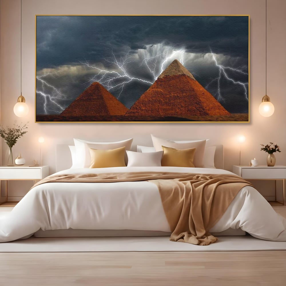 Tablou canvas cu ilustratie cu piramide si fulgere, in rama de aluminiu auriu, pe perete intr-un dormitor