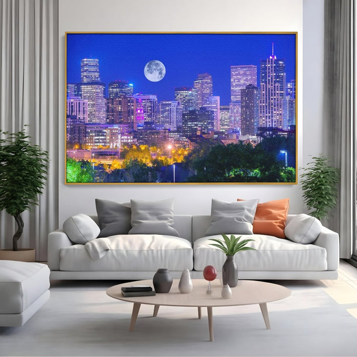 Tablou canvas cu tablou canvas cu peisaj urban nocturn si luna plina, in rama de aluminiu auriu, pe perete intr-un living