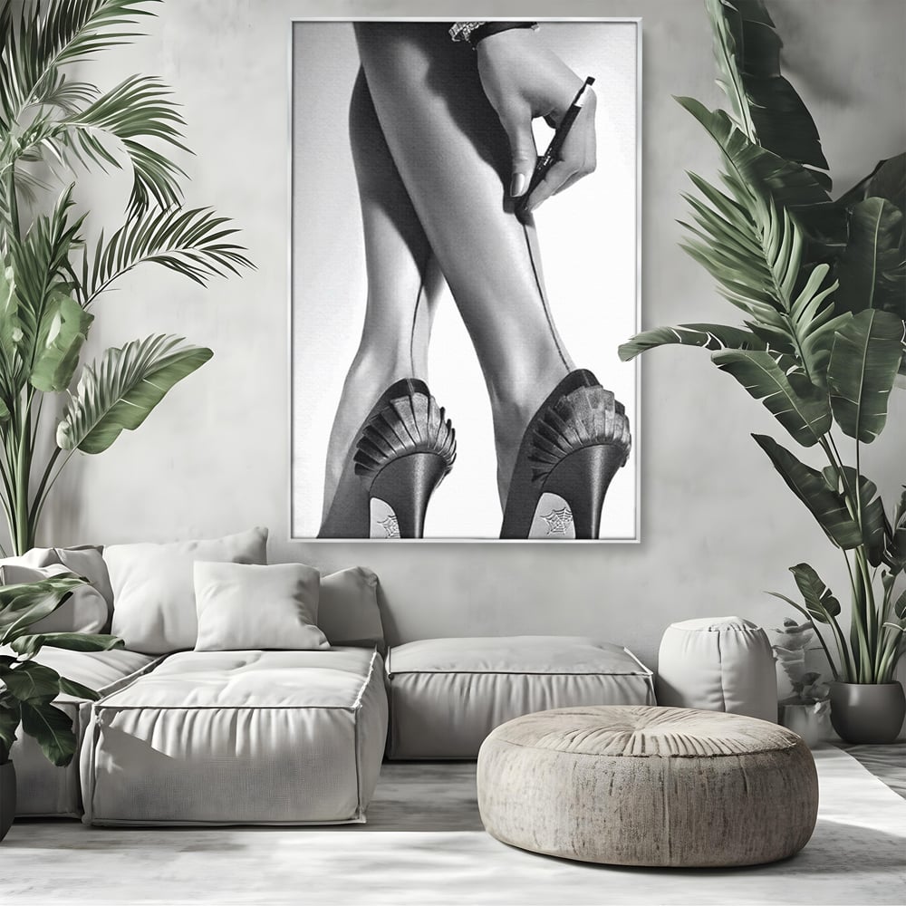 Tablou canvas cu tablou alb-negru picioare dama si pantofi cu toc, in rama de aluminiu argintiu, pe perete intr-un living