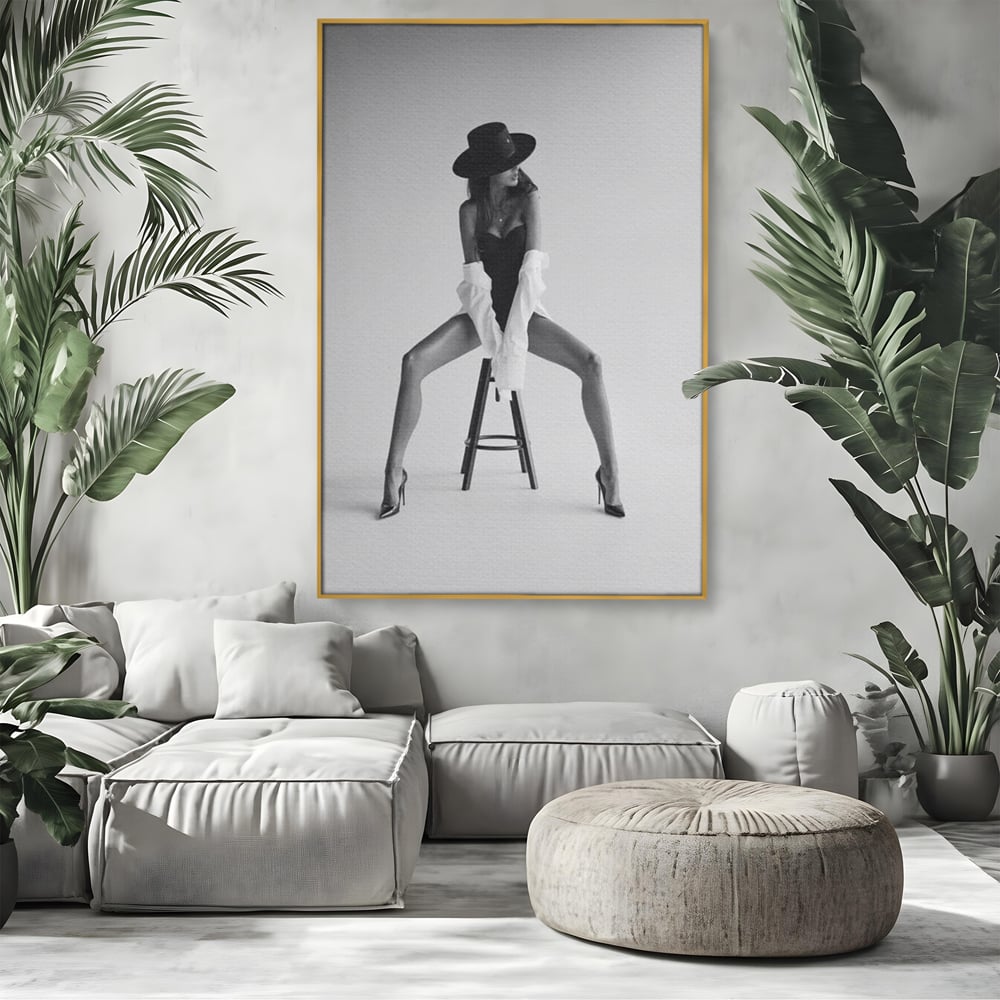 Tablou canvas cu tablou canvas cu femeie pe scaun, in rama de aluminiu auriu, pe perete intr-un living