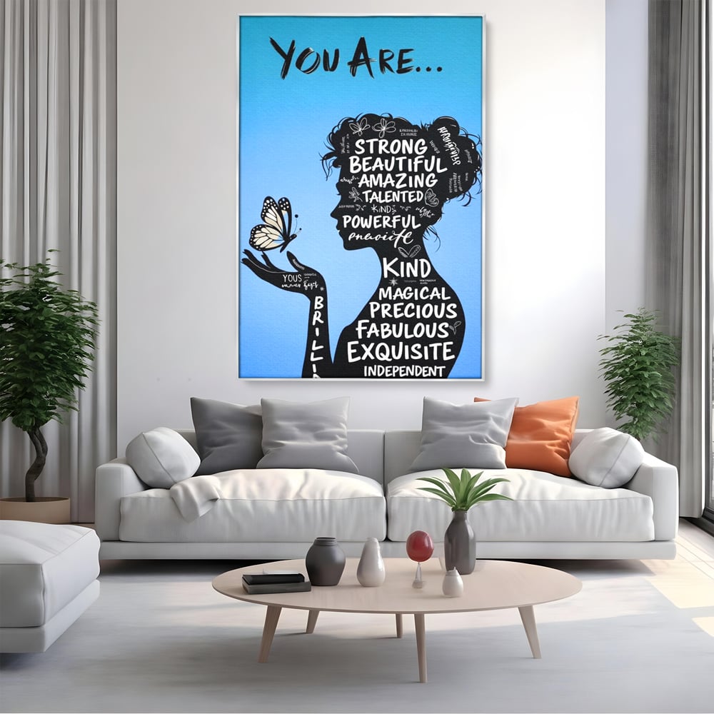 Tablou canvas cu tablou motivational cu portret de femeie si cuvinte, in rama de aluminiu argintiu, pe perete intr-un living