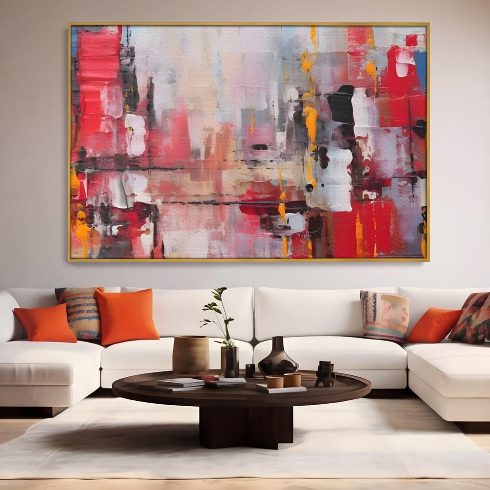 Tablou canvas cu pictura abstracta cu pete de rosu si galben, in rama de aluminiu auriu, pe perete intr-un living