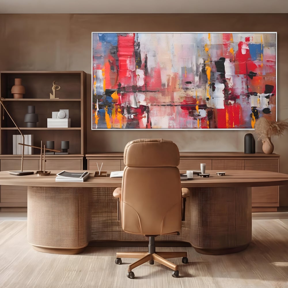 Tablou canvas cu pictura abstracta cu pete de rosu si galben, in rama de aluminiu argintiu, pe perete intr-un birou